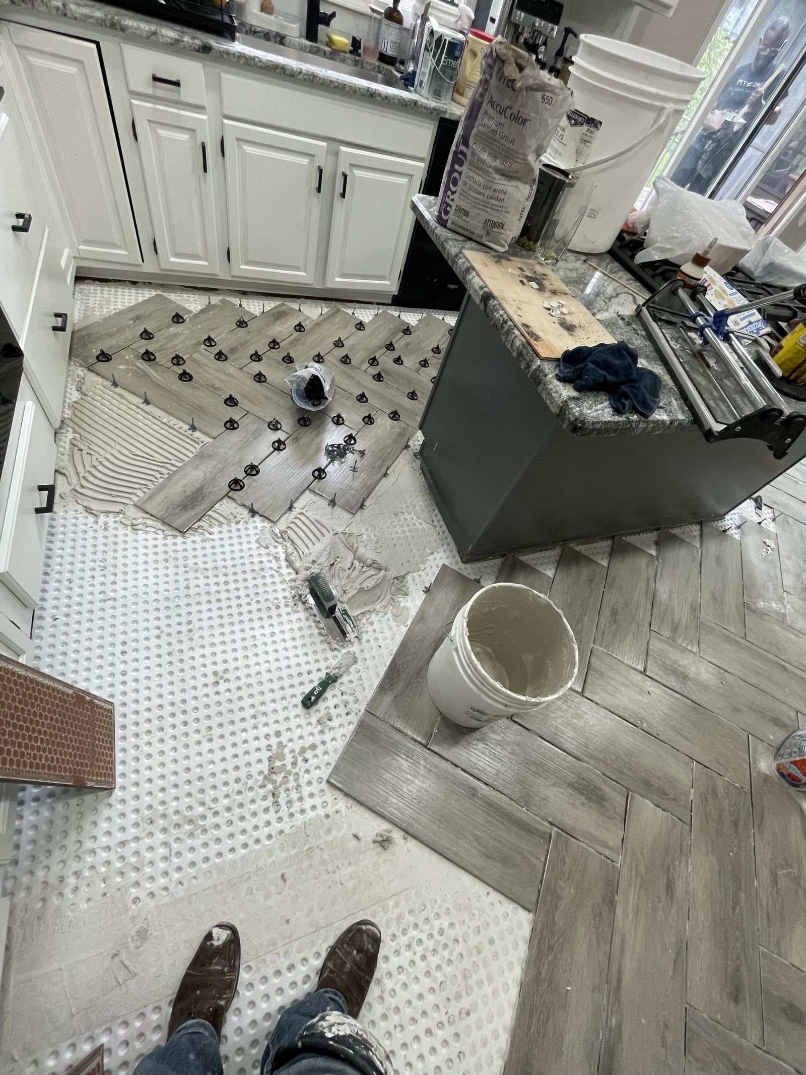 Herringbone floor tile being laid in a kitchen, spacers still in, by the Martinez crew